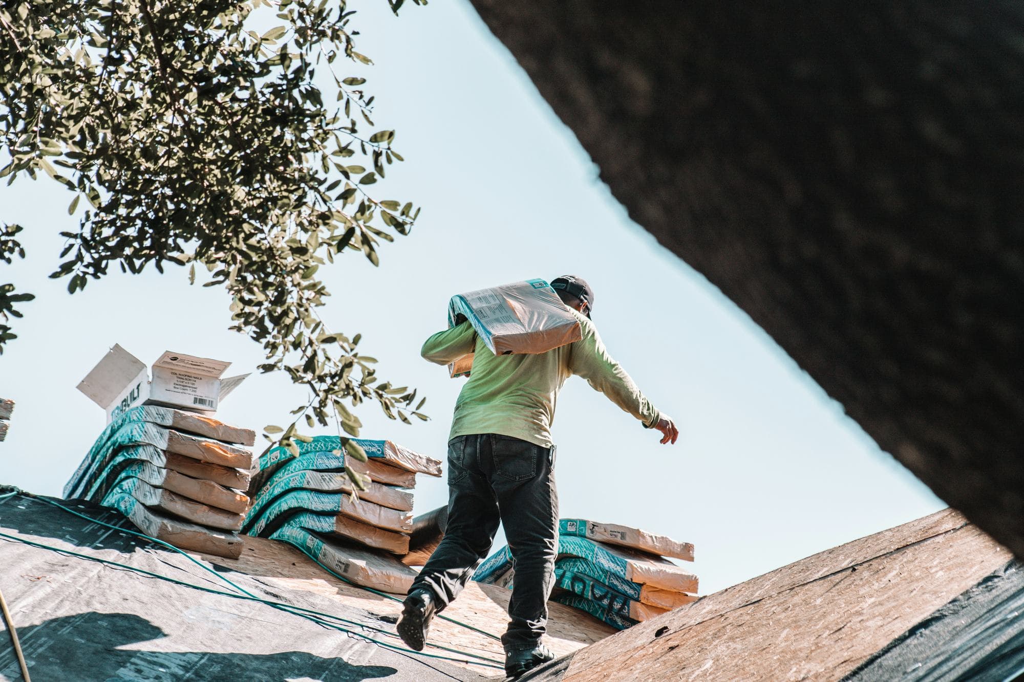 Roofer carrying roofing materials across a roof