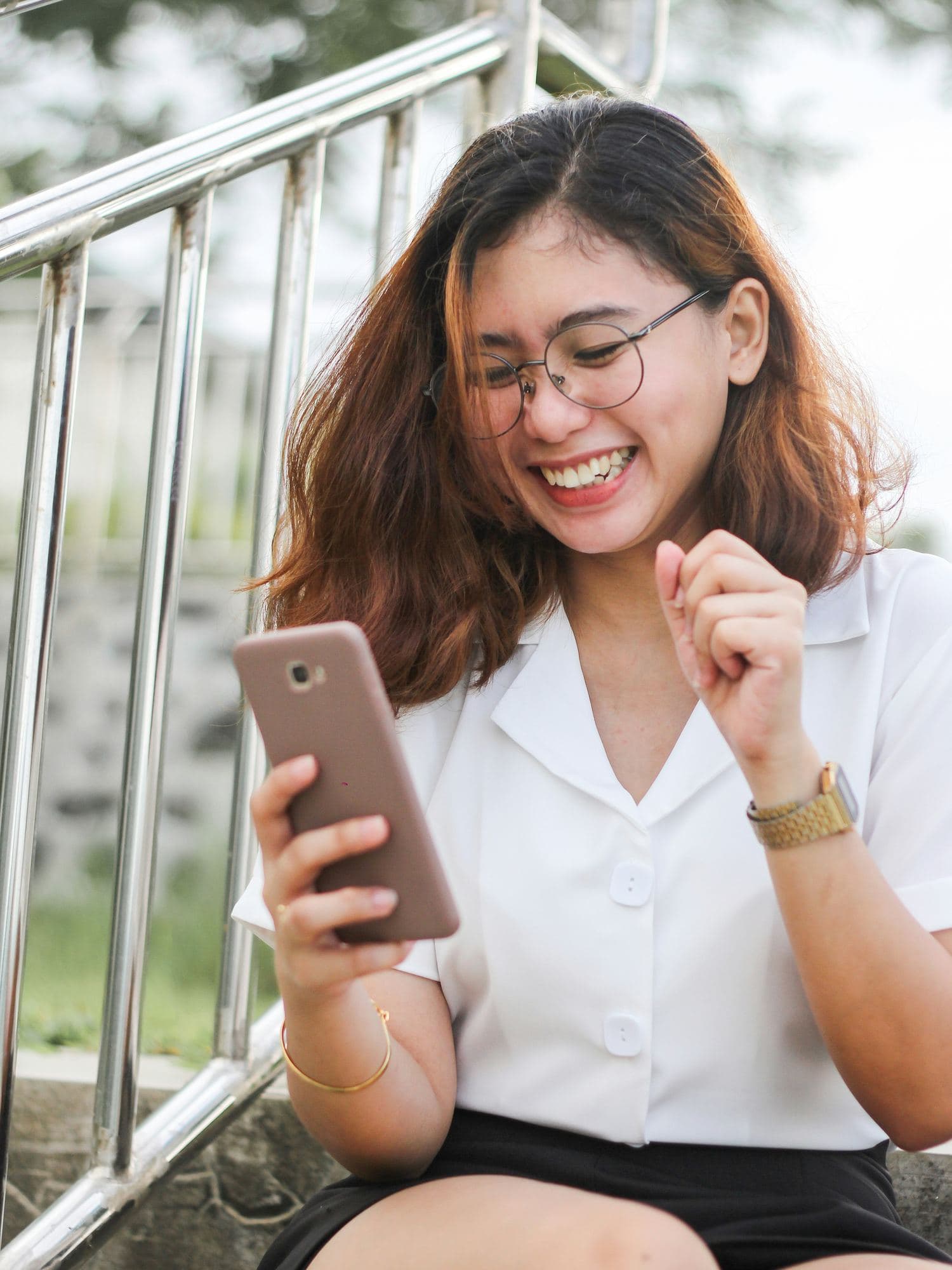 Smiling woman looking at her phone and celebrating