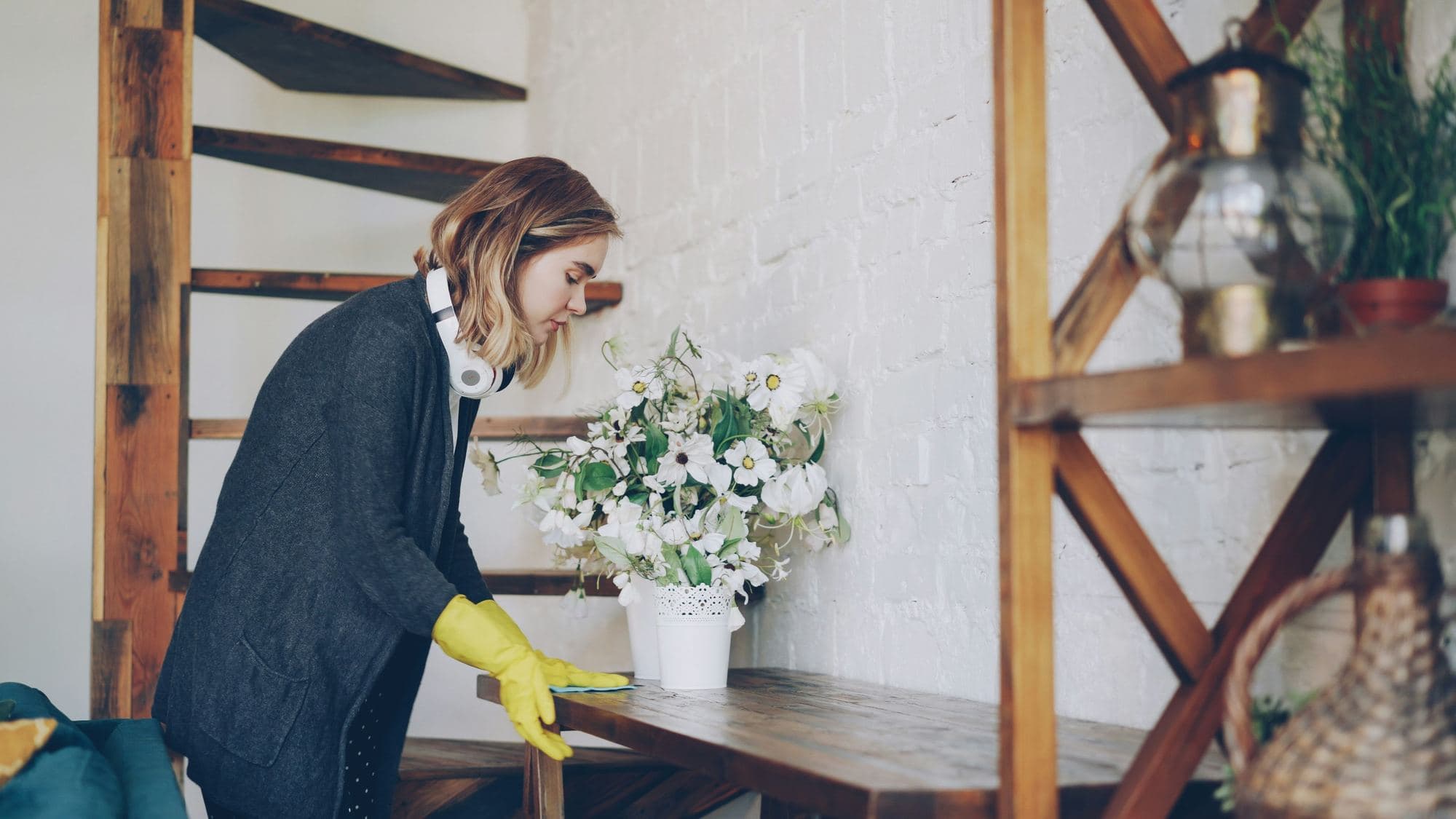 Woman in rubber gloves wiping down a wooden table in a home