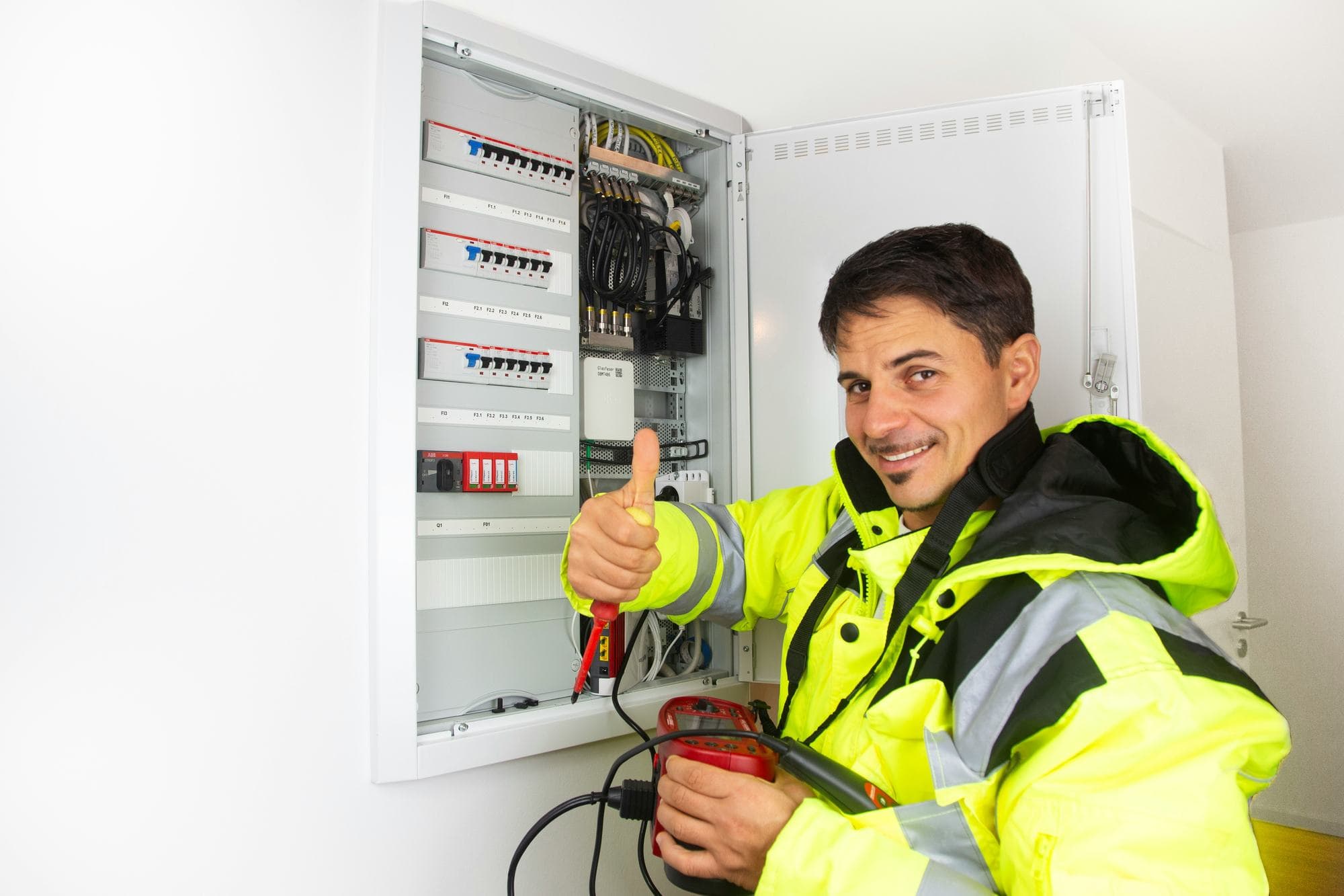 Electrician with a tester at an open consumer unit
