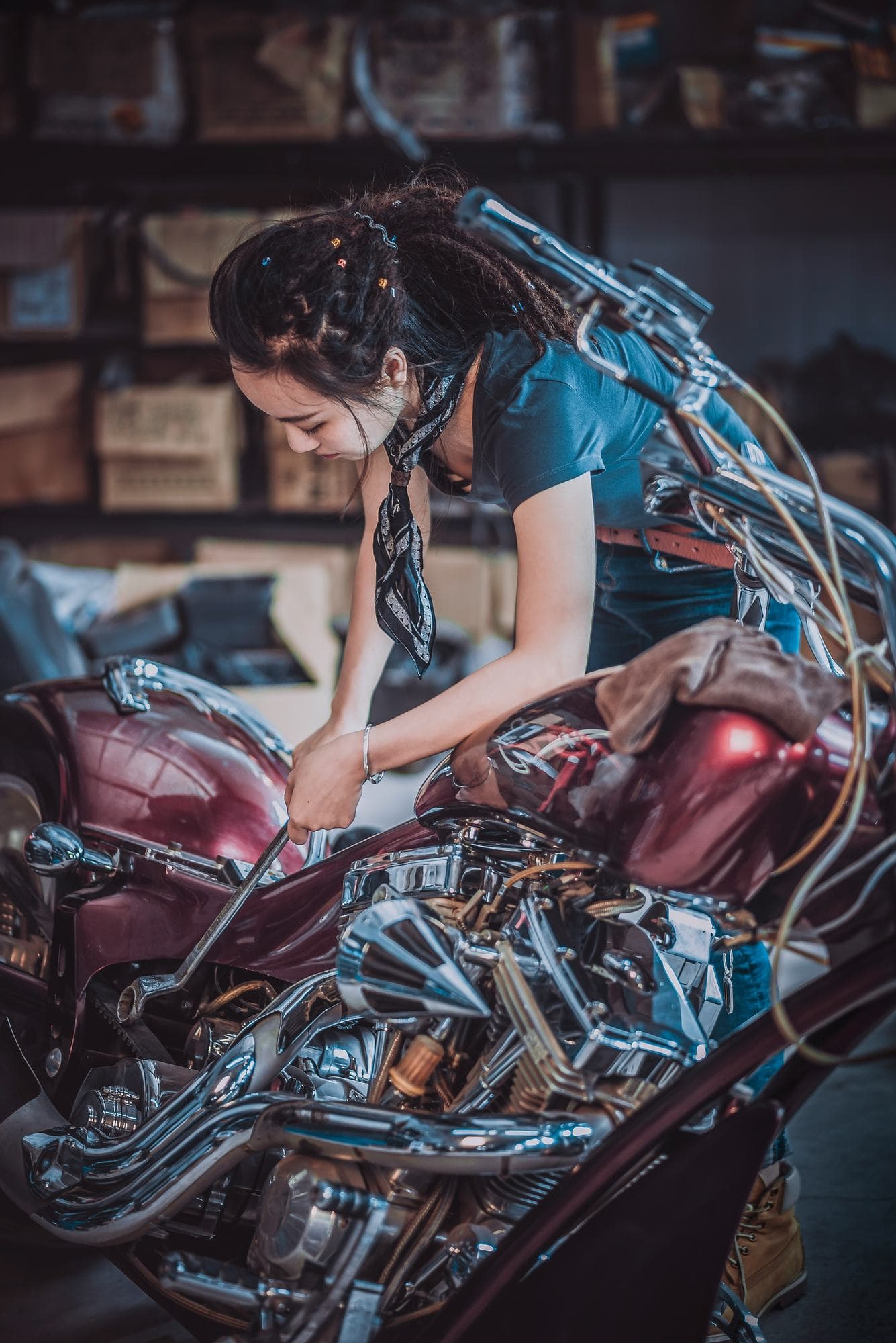 Woman working on a motorbike engine with a spanner